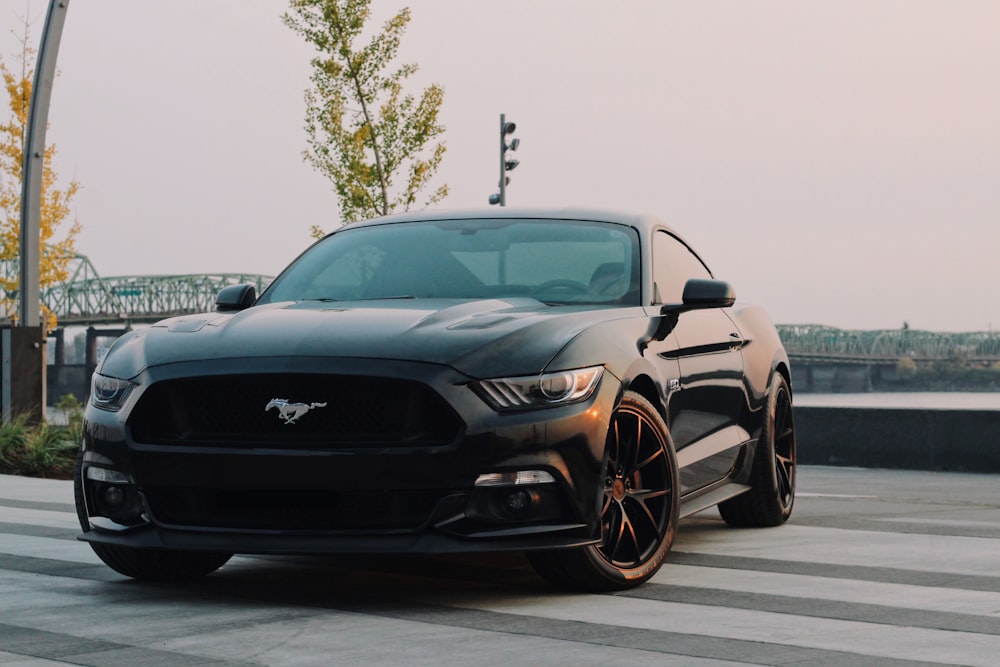 Black coupe with bronze wheels on a quay